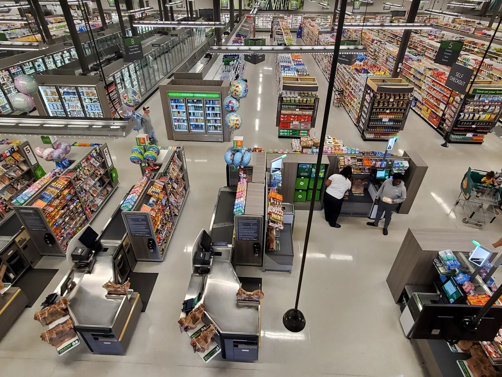 Imagem de câmera de segurança no alto de um supermercado, mostrando corredores e caixas