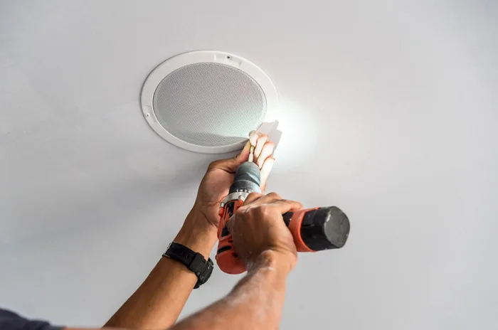 Técnico instalando uma caixa de som embutida no forro